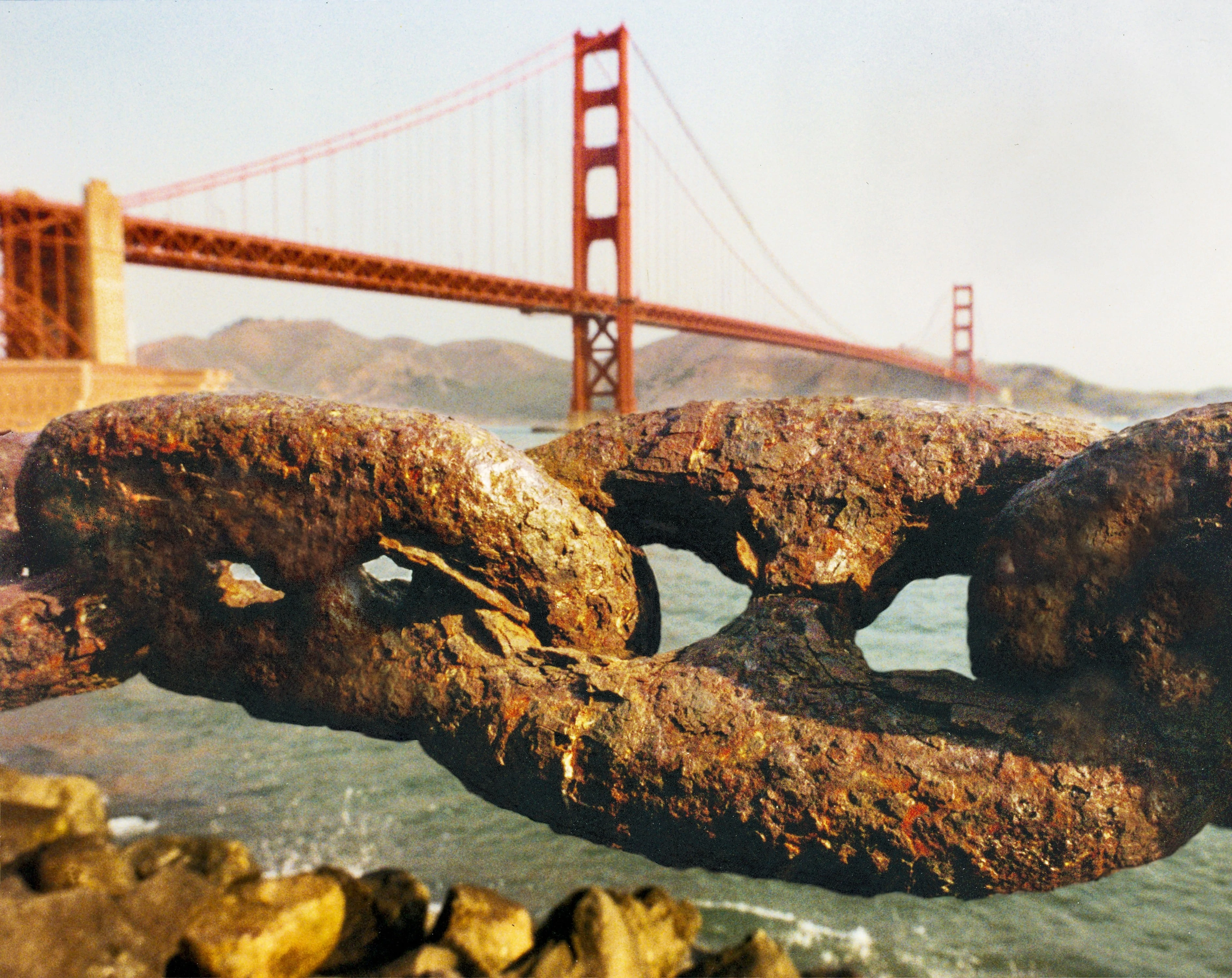 Large rusted chain links with Golden Gate Bridge in background, San Francisco