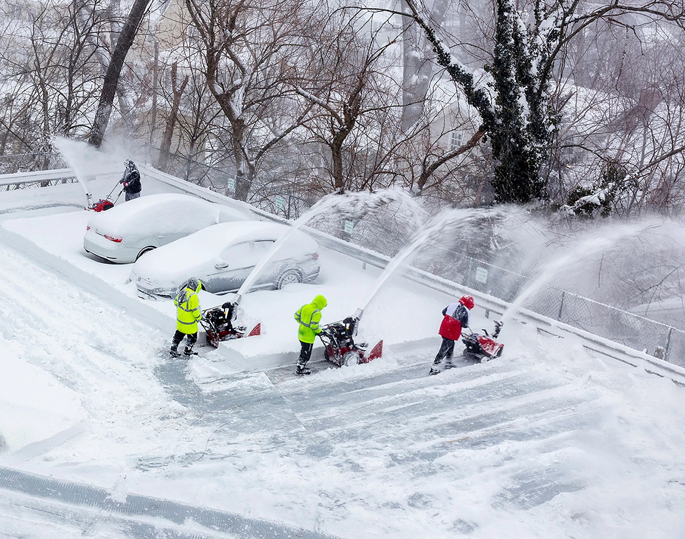 OUT THE WINDOW: Four workers using snow blowers on a parking deck