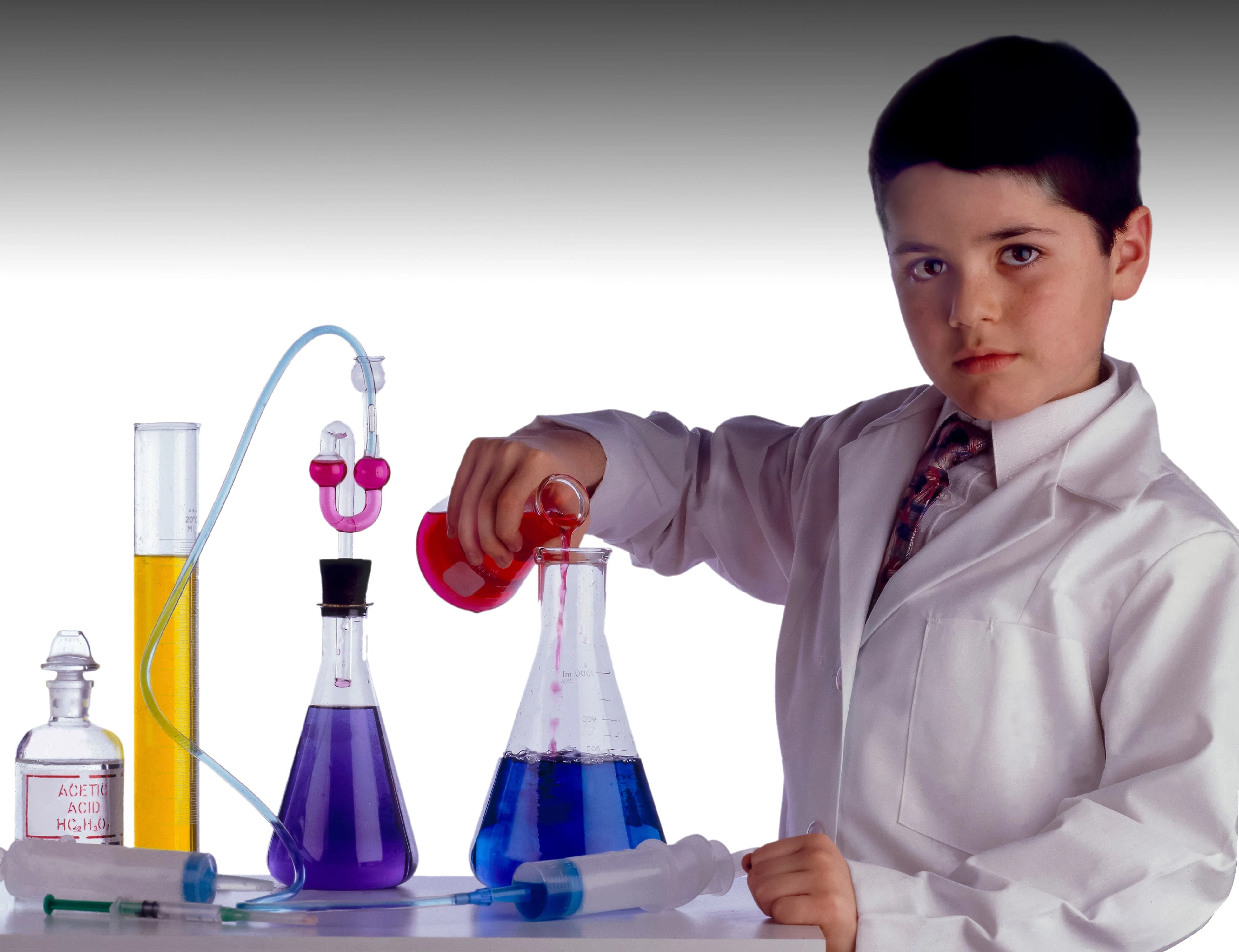 Young boy in white lab coat pouring liquid into beaker